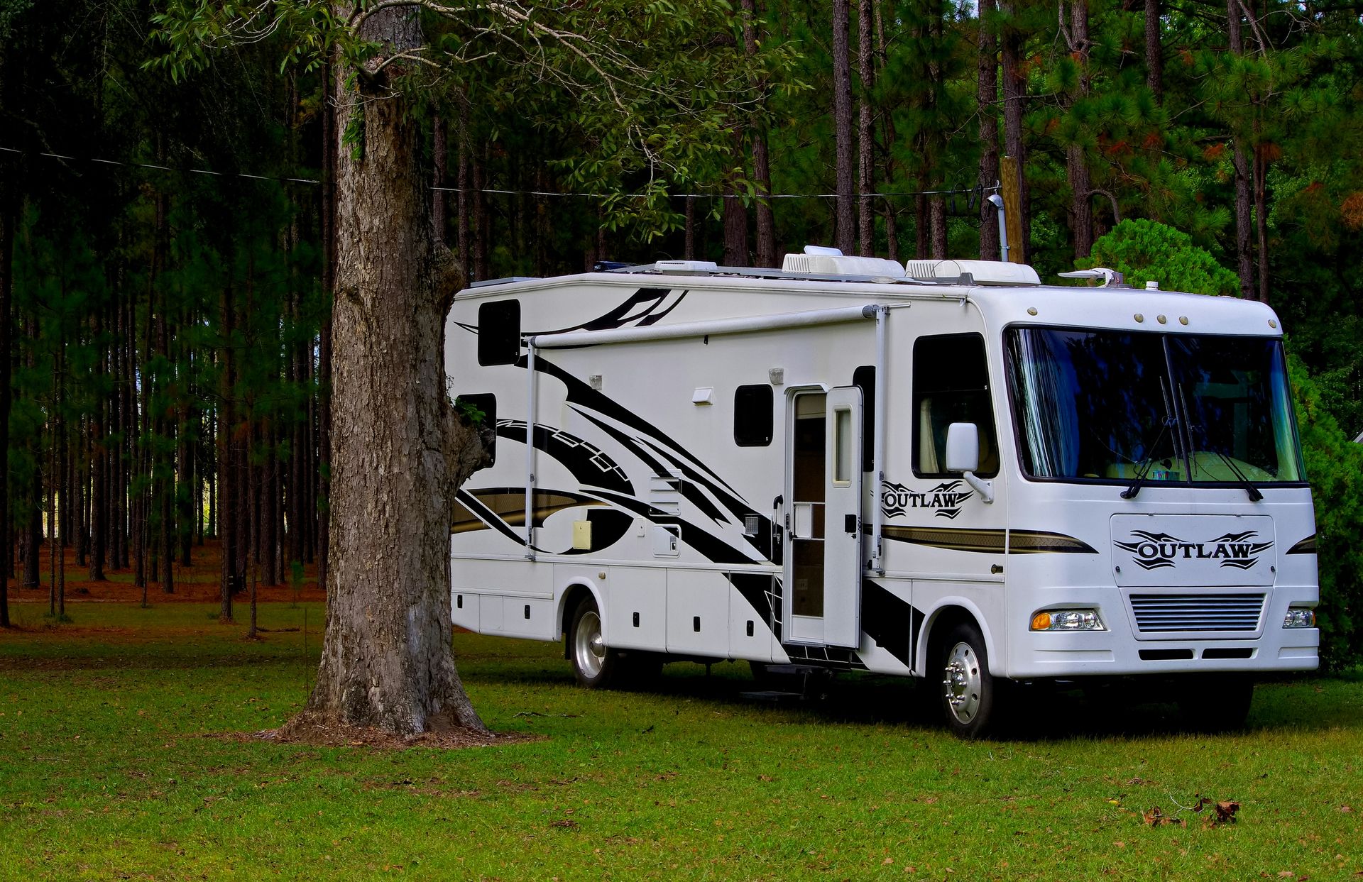 Outlaw RV parked on grass near trees